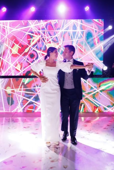 Noivos a dançar num palco com luzes coloridas