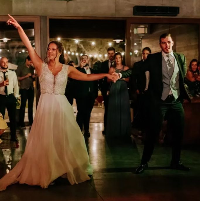 Noiva a apontar e a sorrir durante a dança com o noivo